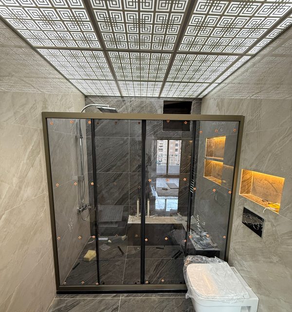 Koyu profilli geniş sürgülü duş bölmesi, ışıklı nişli yeni banyo
